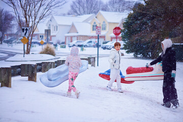 Group of Friends, Children Enjoying Winter Sledding Fun on Inflatable Sleds in a Snowy Suburban Neighborhood. Active Winter Playtime