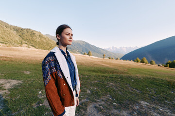 Obraz premium Woman portrait in mountains meadow outdoors nature, young model wearing knitted sweater and jacket standing in vast valley with thoughtful gaze and serene scenery at sunrise for travel lifestyle.