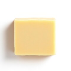 Simple rectangular bar of natural yellow handmade soap resting on a clean white background with shadow