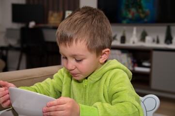 Little boy sitting at the table and eating soup