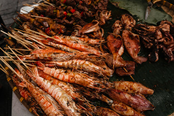 Large shrimp on skewers and an assortment of grilled food side view. Asian street food at the fair