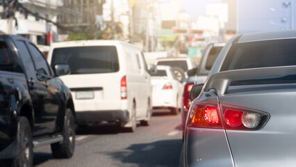 Rear side of silver car with turn on brake light. With bright light of trail light. Traffic congestion on city asphalt roads.