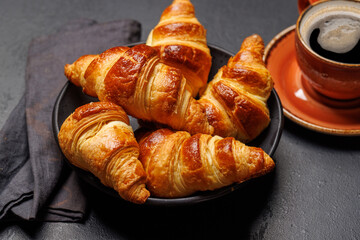 Aromatic croissants in bowl with cup of coffee