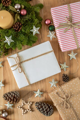 Festive flat lay with wrapped Christmas gifts, pinecones, wreath, and star decorations on a wooden background. Ideal for holiday themes, winter cards, and seasonal designs.