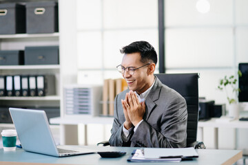 Naklejka premium Asian man using laptop and tablet while sitting at her working place. Concentrated at work.