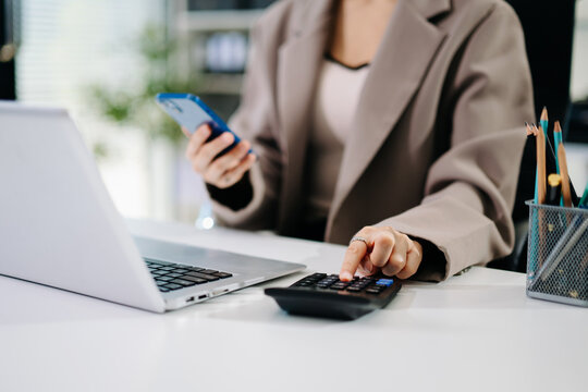 Women counting coins on calculator taking from the piggy bank. hand holding pen working on calculator to calculate on desk about cost