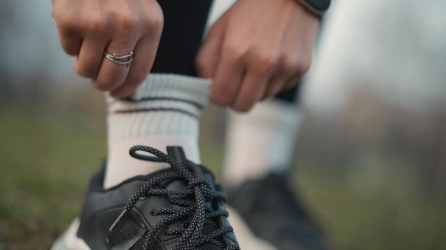 Woman Personalizes Athletic Footwear, Stylish Female Athlete Adjusting Sneakers And Emphasizing Textures, Trendy Woman Customizing Her Sports Socks And Showcasing Athletic Clothing Features