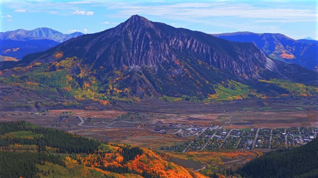 Crested Butte ski resort town drone aerial Mount Crested Butte Colorado autumn fall Elk Range Rocky Mountains quaking colorful Aspen Trees blue skies clouds Coal Creek Kebler Pass backwards pan up