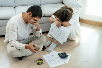 Stressed and headache asian couple with large bills or invoices no money to pay to expenses and...
