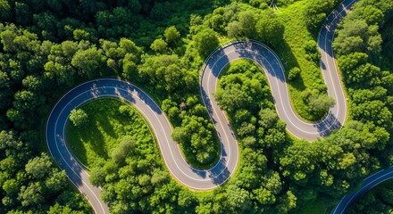 Serpentine mountain road with numerous hairpin turns cutting through a vibrant green forest canopy, captured from above.