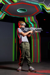 Joyful boy plays laser tag game. Child having fun in game entertainment center.