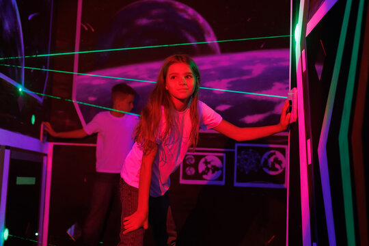 Girl and boy playing a laser labyrinth simulation game. Interactive adventure room.