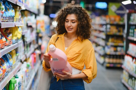 Woman choosing detergent in supermarket aisle