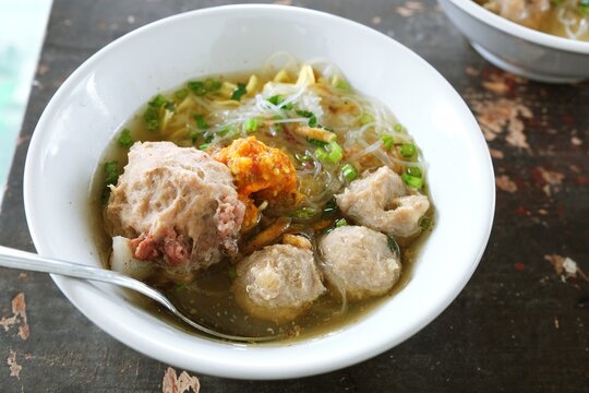 Savory Indonesian bakso meatball soup served with herbs and noodles in a warm flavorful broth.