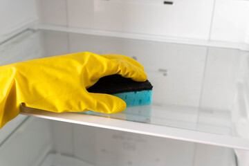 Cleaning a refrigerator shelf with a sponge in a kitchen during the day
