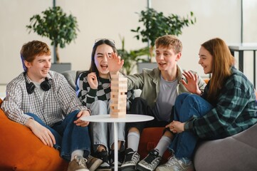 Friends playing exciting game of wooden blocks on table, having fun together