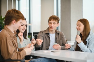 Happy students playing cards in university break room