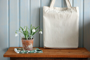 Blank canvas tote bag next to snowdrops for mockup