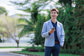 Young asian man smiling holding smartphone looking away