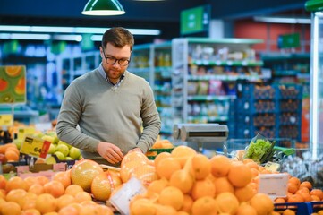 Young man buying groceries at the supermarket. Consumerism concept