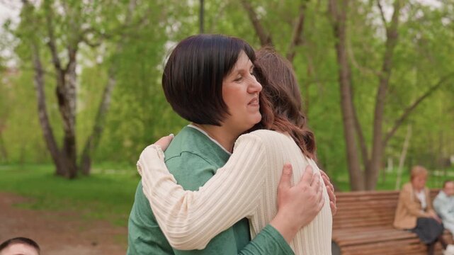 Joyful Reunion With Supportive Heartfelt Hug, Two Women Embrace Happily Amid Peaceful Park Surroundings, Touching Moment Of Reconciliation Captured With Supportive Hugs In Lush Outdoor Setting