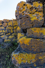 A wall of large rectangular stones is covered with bright brown lichen. Saro, Meskheti, Javakheti, Georgia.