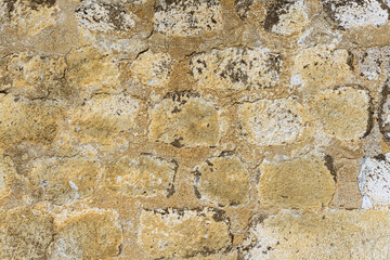 The wall is constructed of light brown round and oval stones bonded with cement and lime mortar. Traces of lichen are visible.