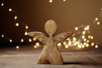 Fototapeta premium Rustic wooden angel figurine on holiday lights