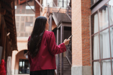 Woman using phone in modern urban alleyway looking away
