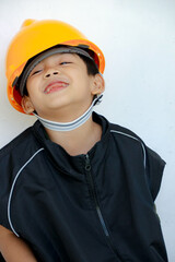 Young Boy Wearing Yellow Construction Helmet Smiling Playfully in Black Work Vest