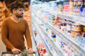 Arab man choosing groceries in supermarket with shopping cart
