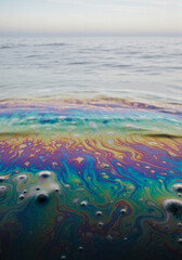 Obraz premium Oil film on ocean water showing colorful rainbow patterns 