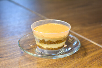 Close up a cup of tiramisu on a wooden table in a warm light at a coffee shop.