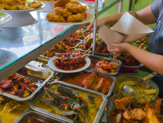Waiter serving side dishes at an Indonesian food buffet stall