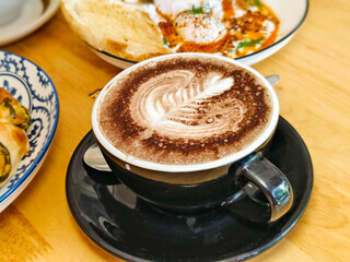 Close up. Hot chocolate in a black cup on a wooden table.