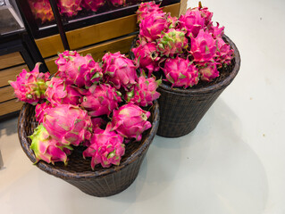 Bright pink dragon fruit is placed in a woven basket at a shop.