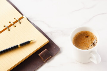 Opened schedule planner, diary, notebook with cup of Coffee on table
