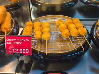 Rows of golden brown crispy chicken balls are displayed for sale.
