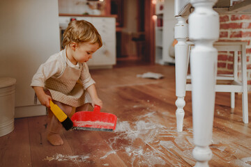 Little girl cleaning up flour mess in kitchen.