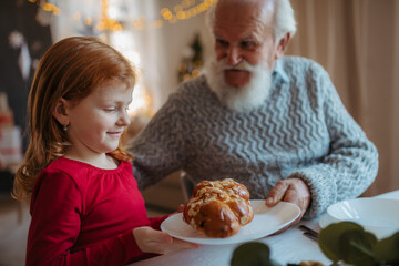 Grandfather offering sweet christmas cake to granddaughter.