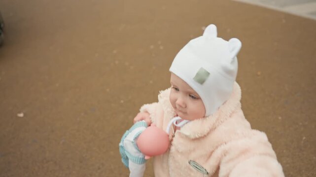 Infant Moves Through Park On Cold Day, Little Toddler Explores Park Environment With Mix Of Curiosity And Caution, Young Child Investigates Outdoor Play Area Carefully On Chilly Weather Day