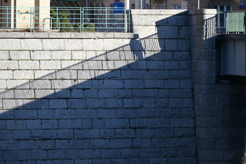 A human shadow and railing on a stone river embankment
