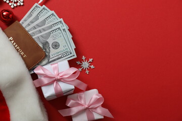 Christmas travel. Top view of passport, money, gift image on red background with space for design.

