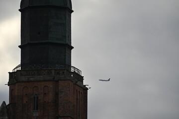 Obraz premium Church basilica tower with a passenger airplane flying in the background 