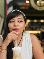 Portrait of Pensive Brunette Woman Enjoying a Sweet Drink in Cafe