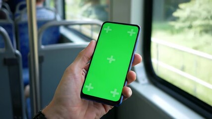 Person holding a smartphone with a green screen inside a moving train, ideal for app promotion or travel vlogs.