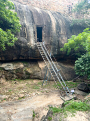 Ancient rock-cut Shiva temple with entrance at the base of massive fortification walls of...