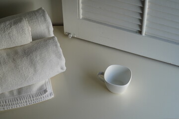Hotel motel setup with towel, cup and window shutter