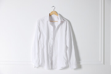 Hanger with creased shirt near white wall