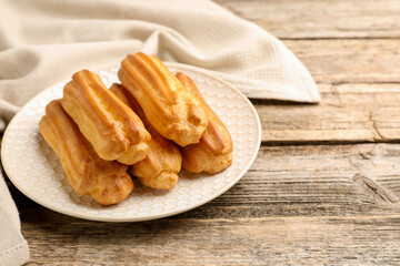 Fresh tasty eclairs on wooden table, closeup. Space for text